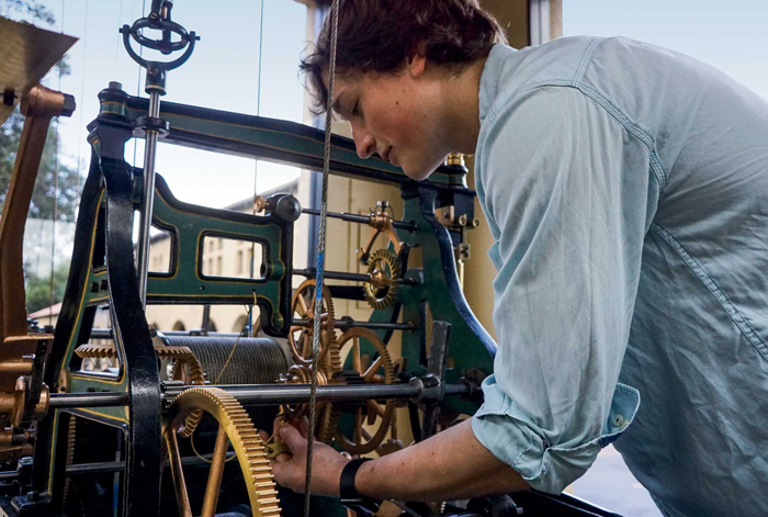Michael Hazard bent over and examining the clock.
